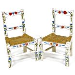 A pair of miniature painted rush seated chairs, each with floral cresting rails, horizontal splats