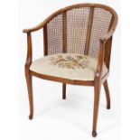 An Edwardian mahogany and bergere tub chair, with overstuffed seat in petit point floral material,