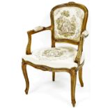 An early 20thC French salon armchair, upholstered to the back and seat in floral material set with a
