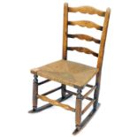 A late 19thC rush seated child's rocking chair, with ladder back, turned supports, turned legs on