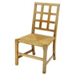 An early 20thC oak Arts & Crafts child's chair, in the manner of Heals, with a lattice back, rush