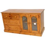 A pine side cabinet, with three drawers aside double glazed doors, with shelves and interior, on a