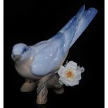 A Lladro figure group of a bird, on flowering tree branch, printed marks beneath, 10cm H.