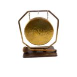An early 20thC brass gong, in an octagonal frame, raised on a rectangular oak base, with clanger,