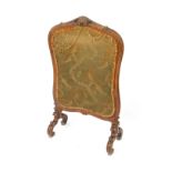 A Victorian mahogany fire screen, fabric in a shield shaped frame, carved with a shell flowers and