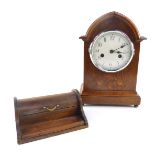 An Edwardian oak and inlaid mantel clock, the circular cream enamel dial bearing Arabic numerals,