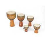 Five graduated wooden and hide bongo drums, with coloured rope twist binding, largest drum 61cm H,