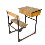 An early 20thC beech and cast iron child's school desk, the writing slope hinged to reveal a box