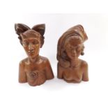 A pair of Balinese carved wooden bust figures of a man and woman, with elaborate head dresses,