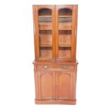 A Victorian mahogany bow front cupboard bookcase, pediment lacking, with two glazed doors, opening