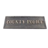A cast iron rectangular 'County - Police' sign, 14cm H, 44cm W.