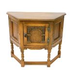 An Old Charm oak Elizabethan style side cupboard, of demi hexagonal form, with a single panelled