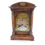 A early 20thC Junghans stained pine mantel clock, brass arched dial with decorative spandrels,