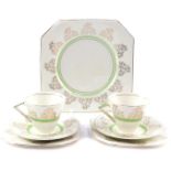 A pair of Art Deco porcelain trios, decorated with gilt floral sprays and green bands, together with