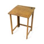 An early 20thC oak child's folding gate leg desk, with pen and ink well recesses and drop flap