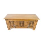 An Old Charm oak coffer, with a hinged lid and levered drop down panelled front, decorated with