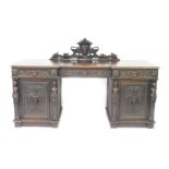 A Victorian oak break front sideboard, the back carved with masks and fruit, over three frieze