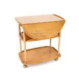 An Ercol light elm three tier trolley, the top with drop flaps, raised on turned supports, on