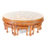 An Oriental hardwood oval occasional table, the glass protected top carved with figures in a garden,