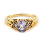 A 9ct gold and pale blue sapphire ring, oval cut in a high claw setting, with diamond set shoulders,