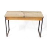 An early 20thC oak and cast iron framed child's double desk, with one long pen recess, two ink