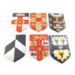 Six plaster shield shaped wall plaques, displaying armorials, including Cambridge University and The