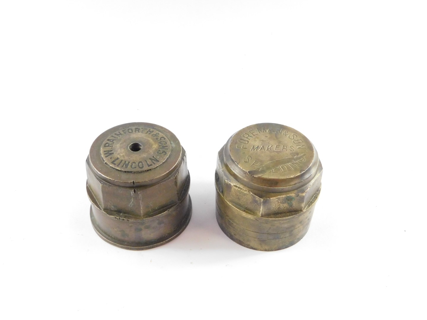 Two brass carriage wheel hub nuts, stamped Foreman & Son Makers Spalding, and W. Rainforth & Sons