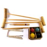 A croquet set, comprising four wooden mallets, four balls, centre peg, and six metal hoops, boxed.