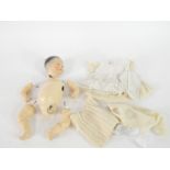 A German porcelain headed doll, with brown eyes, composition body, with clothes, 30cm H. (AF)