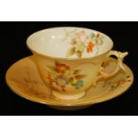 A Grainger & Co Worcester blush ivory spur handle tea cup and saucer, decorated with flowers,