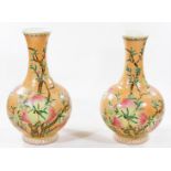 A pair of Chinese peach ground bottle vases, of large size, each bulbous body decorated with