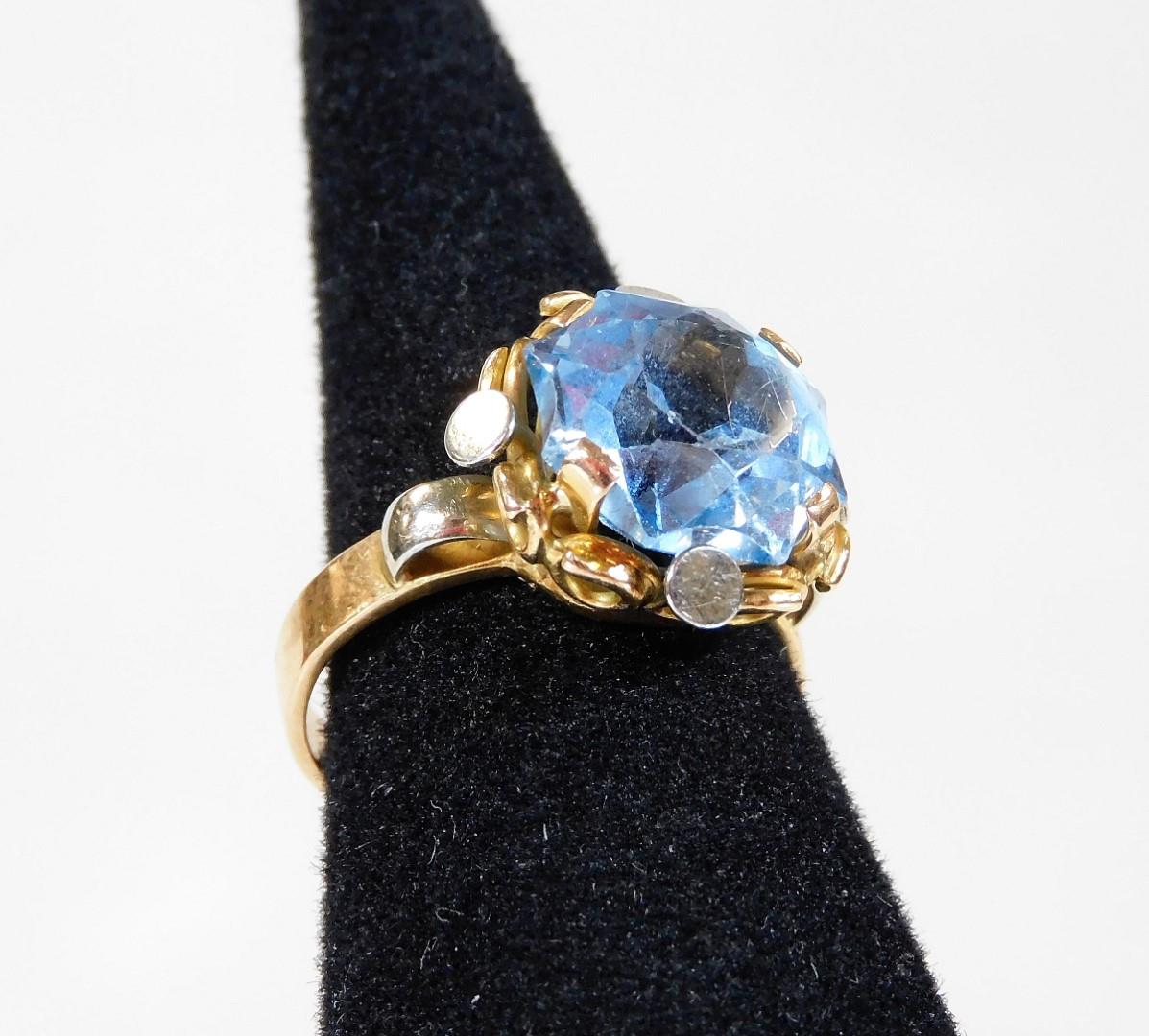 An 18ct gold cluster ring, with central pale blue stone in four claw setting, with white and yellow