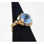 An 18ct gold cluster ring, with central pale blue stone in four claw setting, with white and yellow