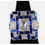 A modern Art Deco style dress ring, of chunky design set with blue and white paste stones, ring size