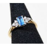 A 9ct gold dress ring, with central rectangular cut blue topaz stone, flanked by three white stones