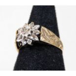 A 9ct gold dress ring, with central flower design, set with illusion set white stones, with etched a