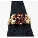A 9ct gold garnet bow ring, with central garnet flower, with bow to either side, ring size P½, 3g al