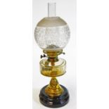 A Victorian brass oil lamp, with clear glass, faceted reservoir, stencilled shade and ceramic base,