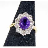 An amethyst and diamond cluster ring, with central oval cut amethyst surrounded by ten round brillia