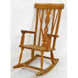 An early 20thC lightwood rocking chair, with comb top, pierced vertical splat, shaped arms and seat