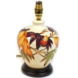 A Moorcroft pottery table lamp, set with autumnal leaves on a wooden base, 30cm H.