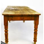 A late 19thC pine plank top kitchen table, the rounded top raised on turned legs, with drawer to the