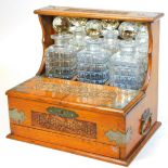 An early Edwardian oak three bottled tantalus, in heavily carved oak case, with metal mounts and fro