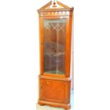 A mahogany finish corner display cabinet, with broken pedimented top and urn finial.