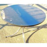 A black table of circular form, on chrome legs.