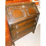 A stained oak bureau, with carved bureau top and three drawer base.