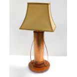 An Arts and Crafts type copper and oak table lamp, of twin handled hammered form, raised on a