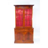 A Victorian flame mahogany cupboard bookcase, the outside pediment over two glazed doors, opening to
