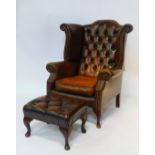 A Georgian style brown tan leather wing armchair, with button back and loose seat, raised on