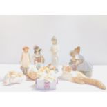 A group of Nao porcelain figures, including two girls with a doll, girl cello player, two puppies,